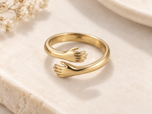 Gold Embrace Ring on an ivory stone surface
