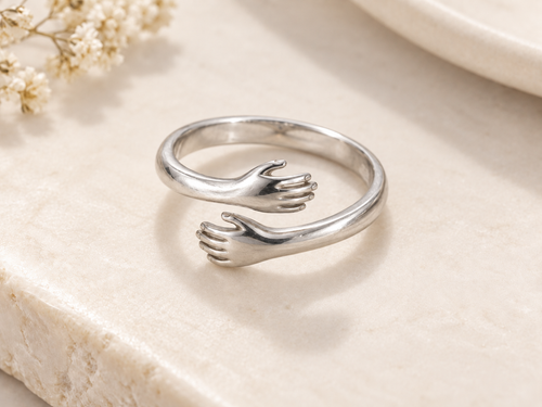 Silver Embrace Ring on an ivory stone surface